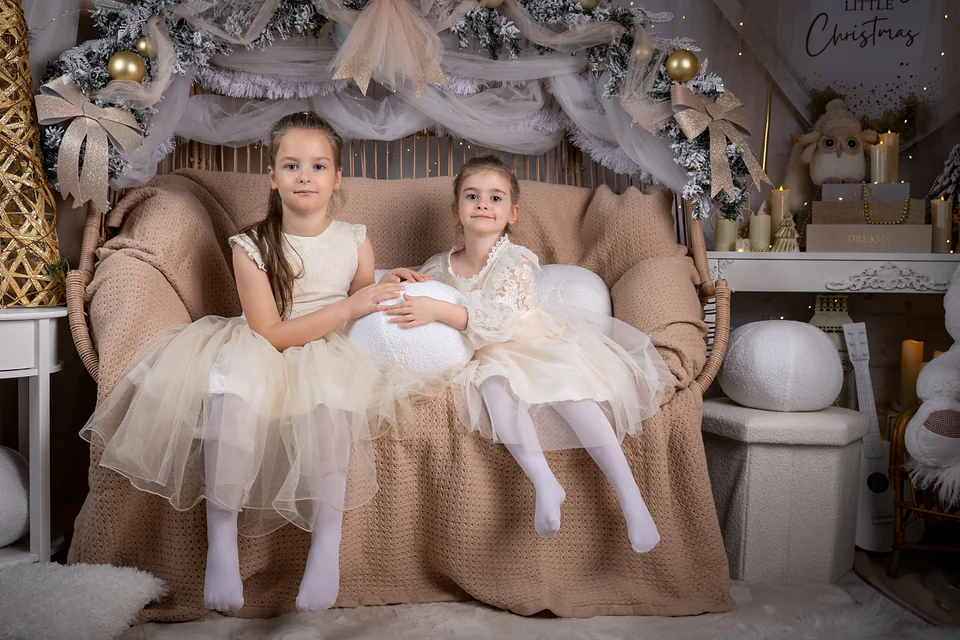 Surori în rochițe de tul ivoire pe canapeaua de răchită, sub ghirlanda ninsă cu globuri aurii — fotografie de Crăciun Oradea, Lavinia Pavel Photography