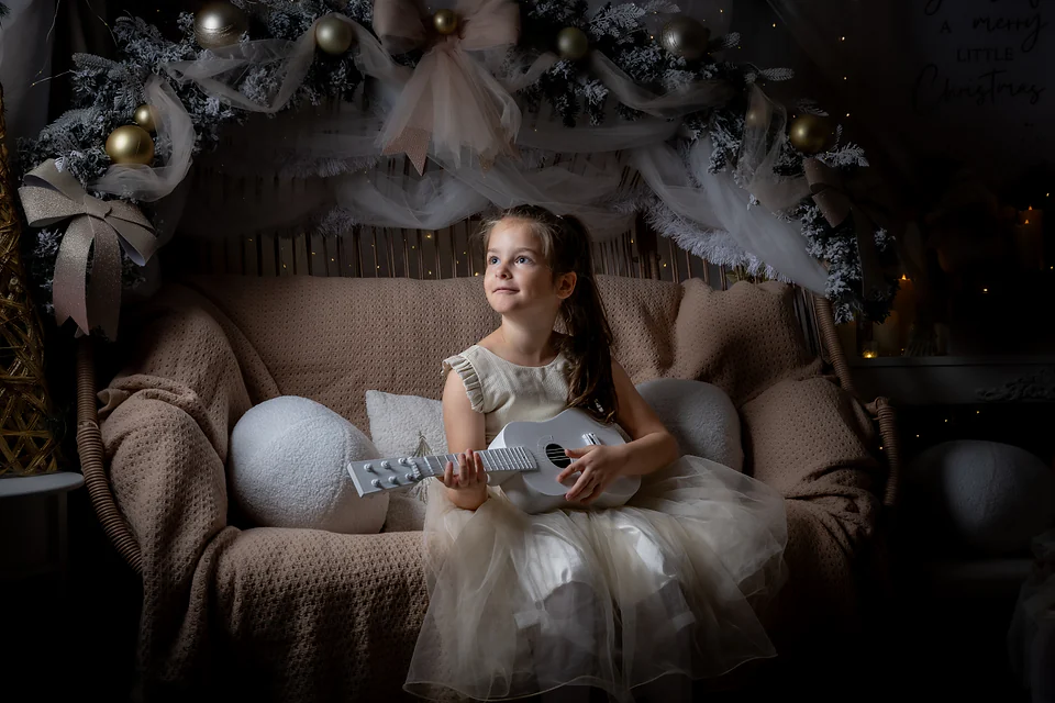 Portret de Crăciun în lumină caldă: fetiță cu o chitară albă pe canapeaua de răchită — Lavinia Pavel Photography, Oradea