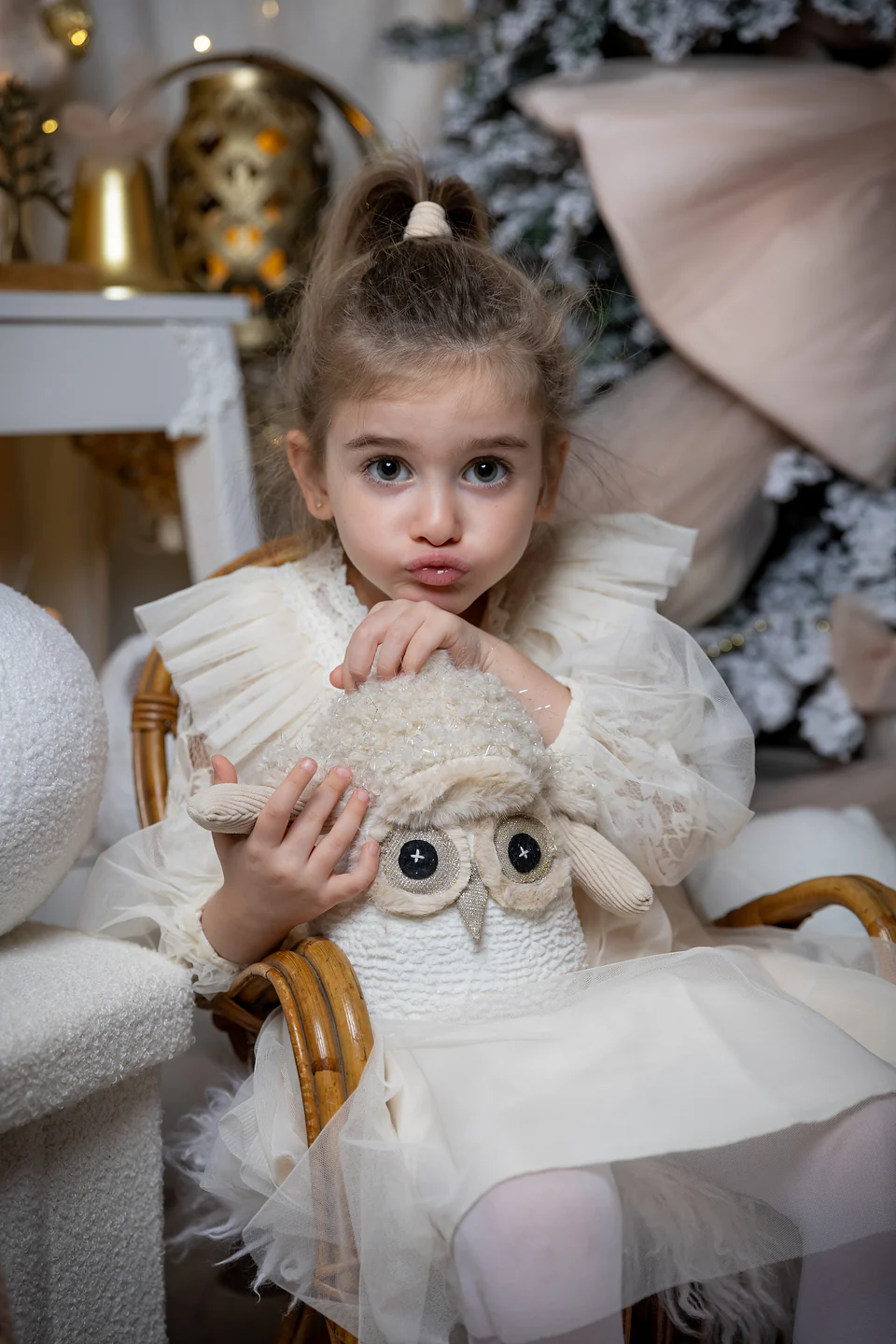 Portret de aproape al unei fetițe care ține o bufniță de pluș, decor de Crăciun ivoire și auriu — fotografie de Crăciun Bihor