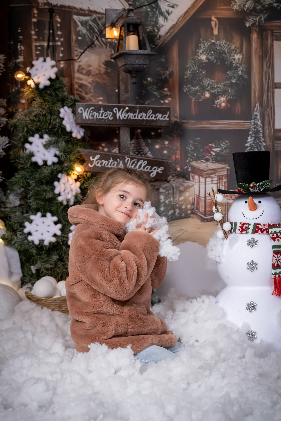 Fetiță ținând un fulg de nea lângă omul de zăpadă și indicatorul Winter Wonderland — ședință foto de Crăciun Oradea, Bihor