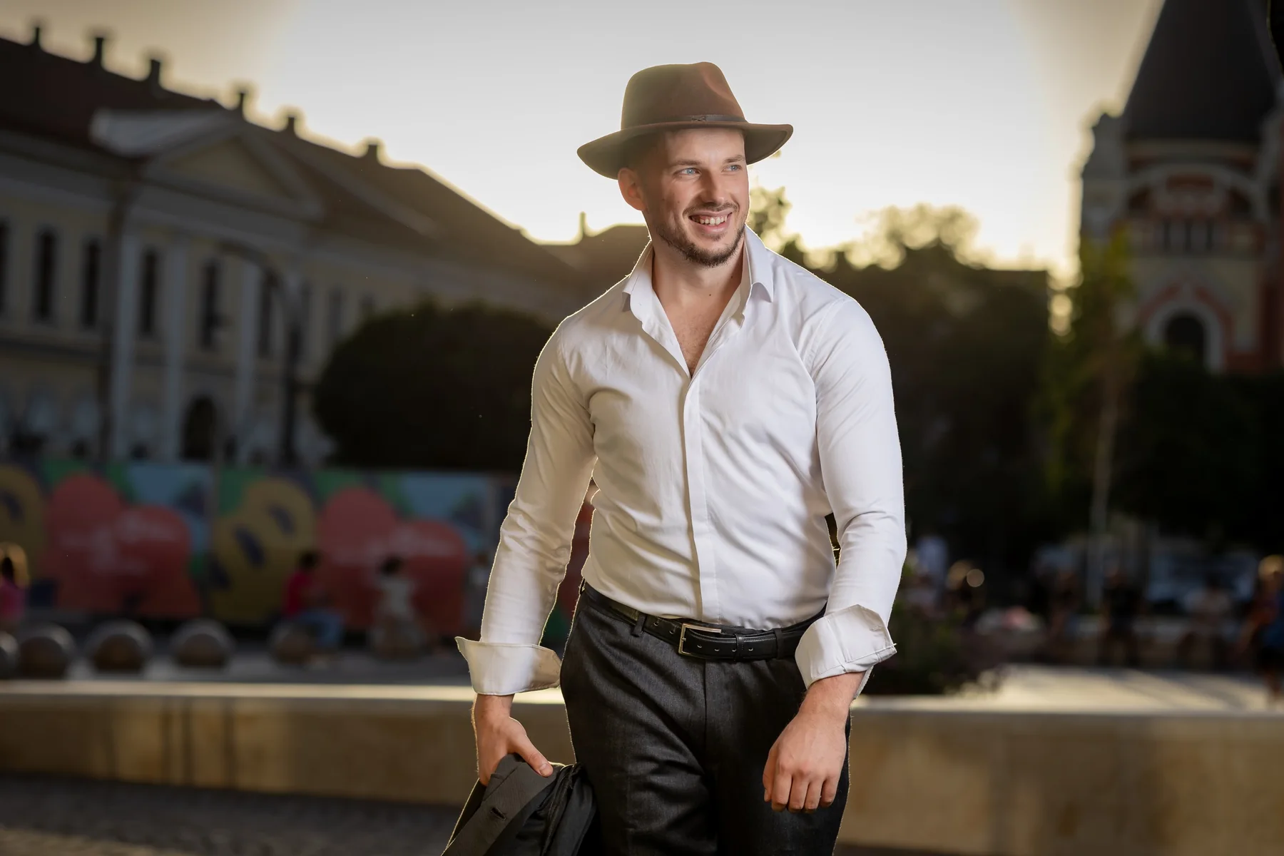 Portret zâmbind cu pălărie maro, lângă spațiul verde — ședință foto în centrul Oradiei