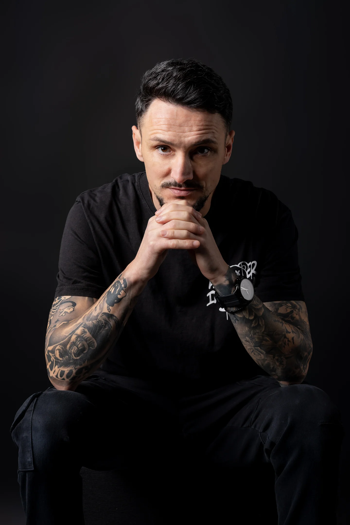 Portret în tricou negru, cu mâinile împreunate lângă față — fotografie business în Oradea