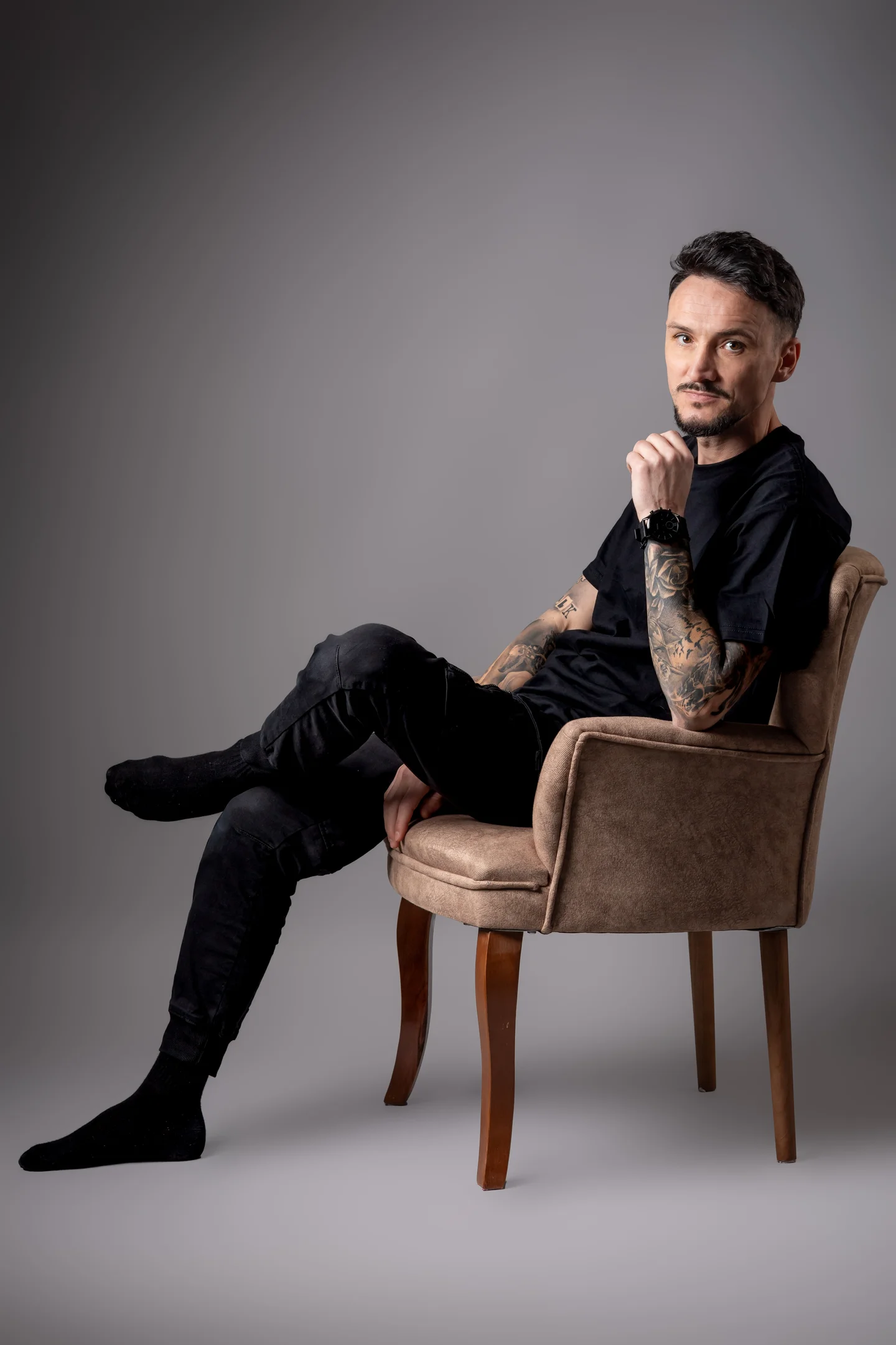 Portret în fotoliu, în ținută neagră, pe fundal gri — fotografie business în Oradea