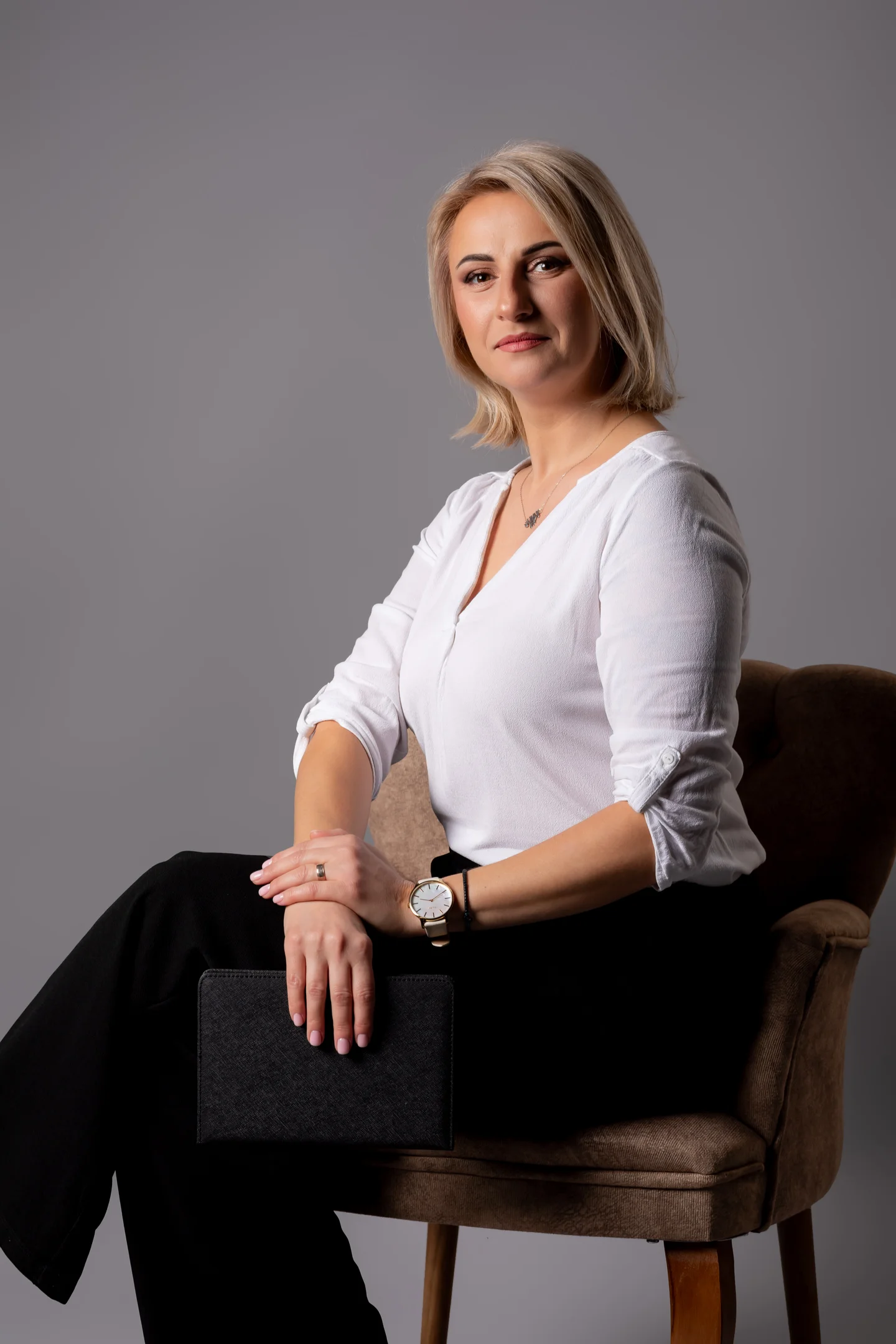 Portret în fotoliu, în bluză albă, cu lumină laterală — fotografie business în Oradea