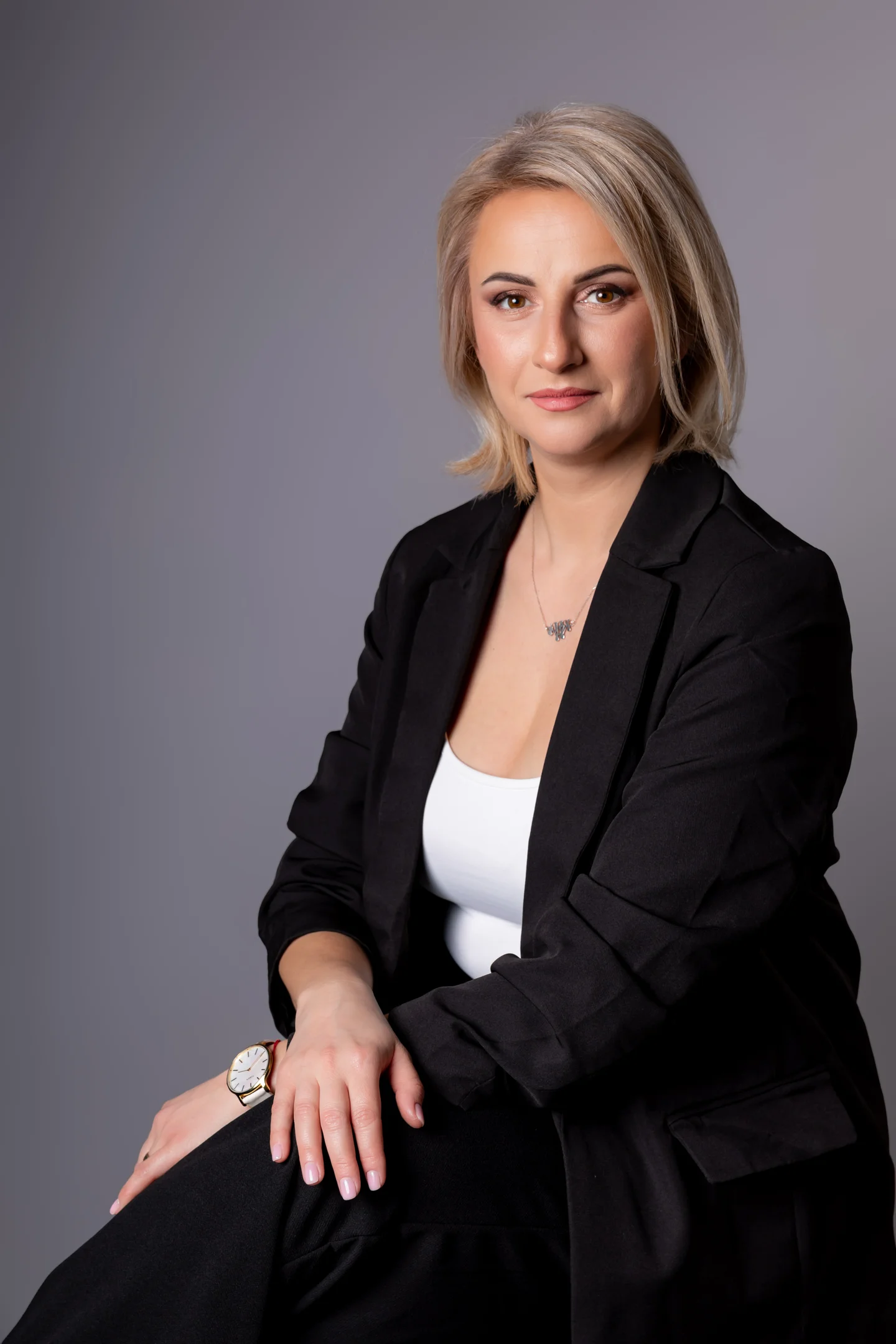 Portret în sacou negru, așezată, pe fundal gri — fotografie business în Oradea