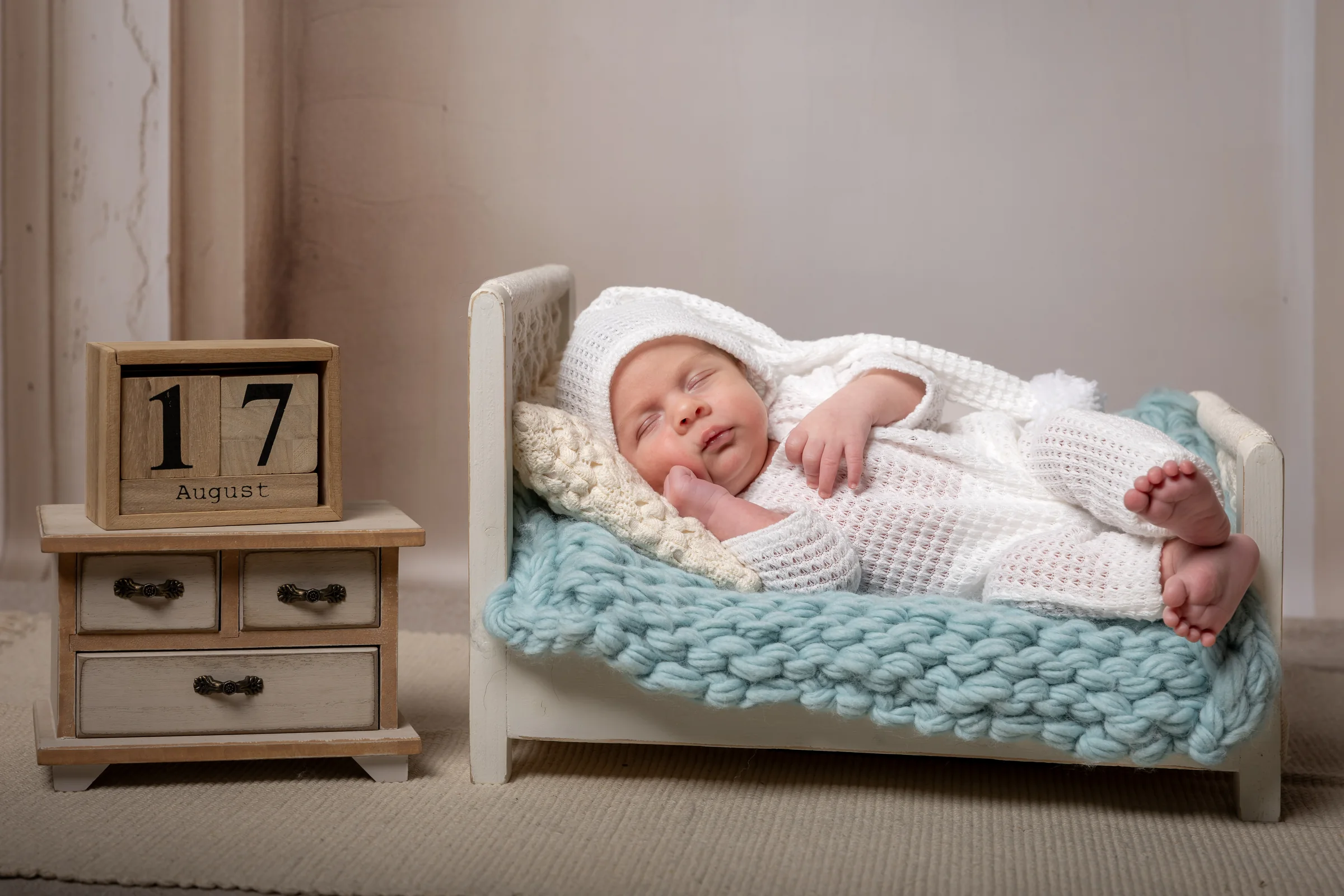 Nou-născut adormit într-un pătuț alb, lângă cuburi decorative — studio foto newborn Oradea