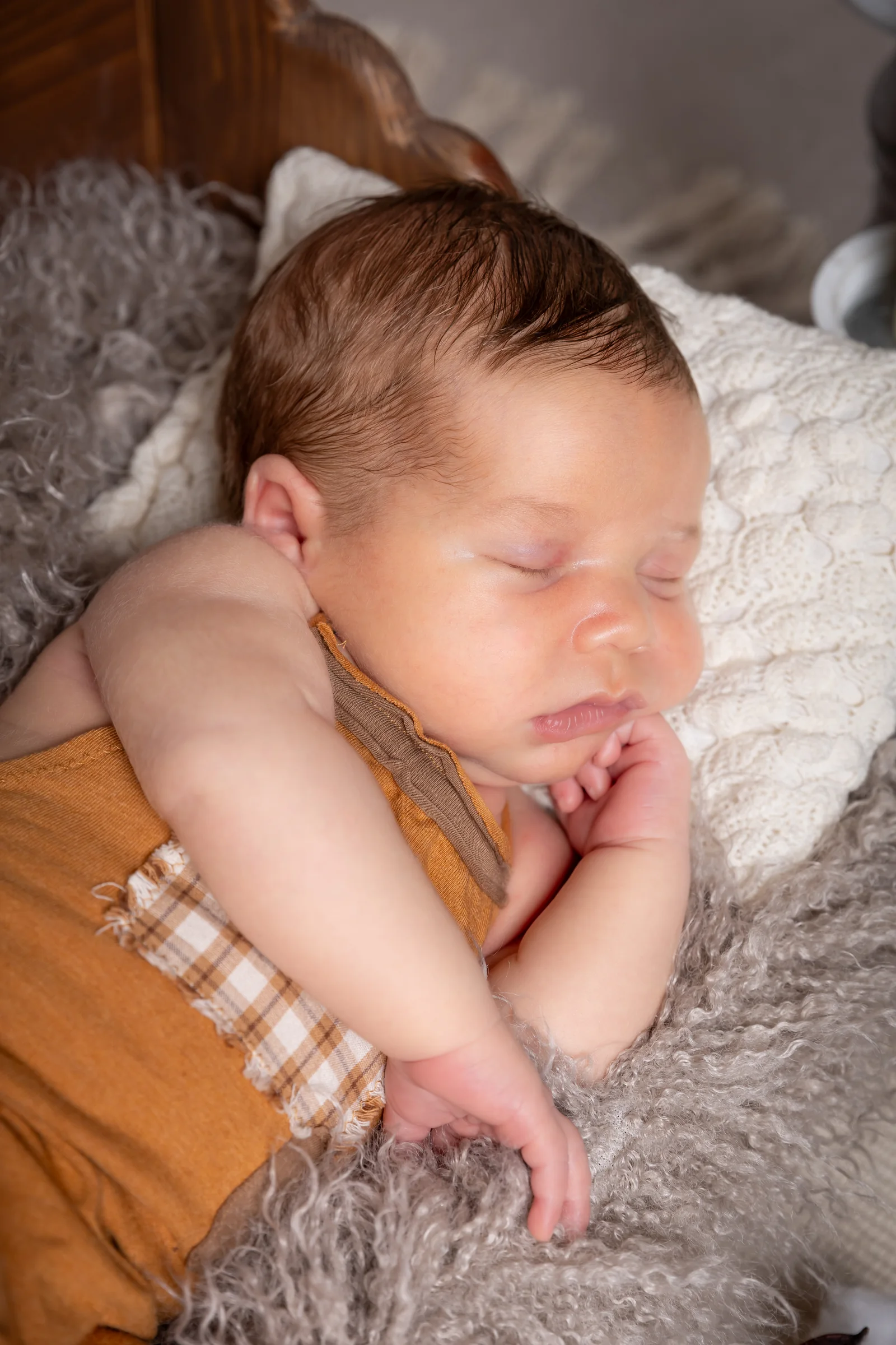 Bebeluș adormit pe o parte, în tonuri calde de maro — fotografie newborn în studio
