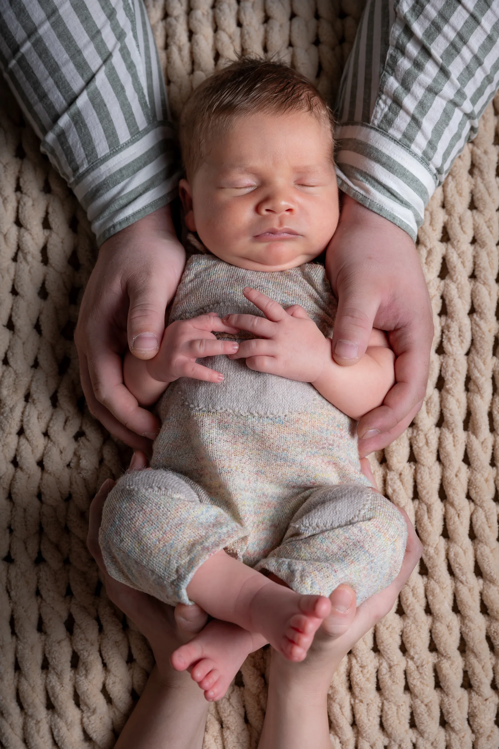 Bebeluș adormit în brațele părinților, fotografiat de sus — ședință foto de familie cu nou-născut