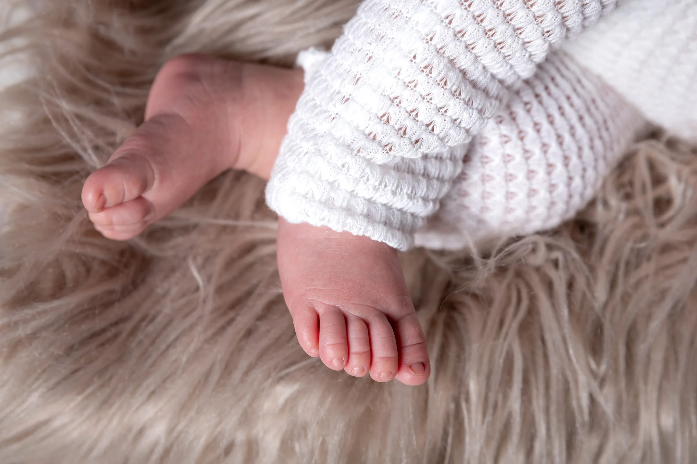 Detaliu cu piciorușele bebelușului în costumaș tricotat — ședință foto newborn