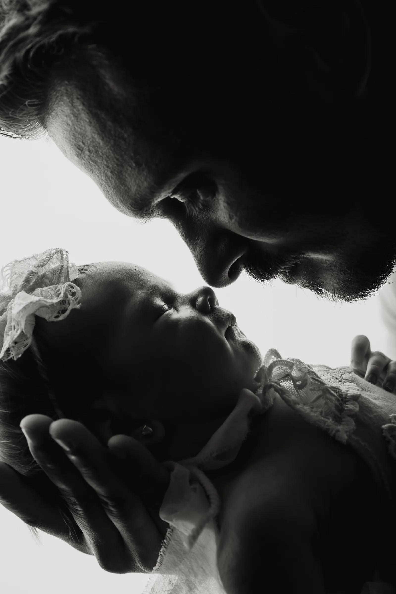 Tată apropiindu-și chipul de nou-născut, portret alb-negru — fotografie de familie Oradea